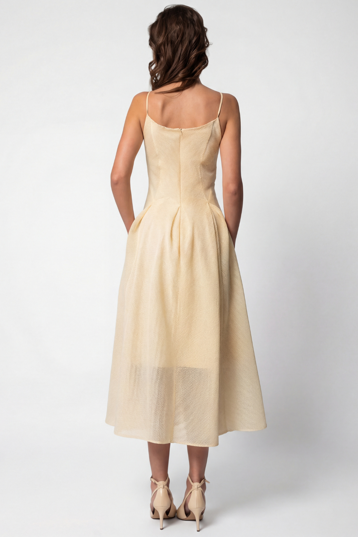 Woman wearing a light yellow dress against a white background