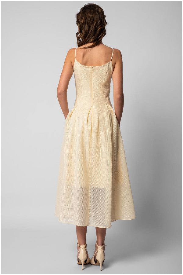 Back view of a woman wearing an ivory elegant midi dress sleeveless A-line midi dress with delicate straps and a fitted bodice.