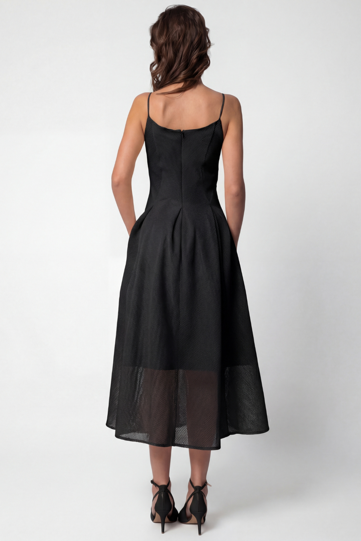 Woman wearing a black dress with sheer panels on a white background