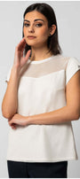 Woman wearing Aria Short-Sleeve Blouse in White with mesh detail and button accents on sleeves against gray background