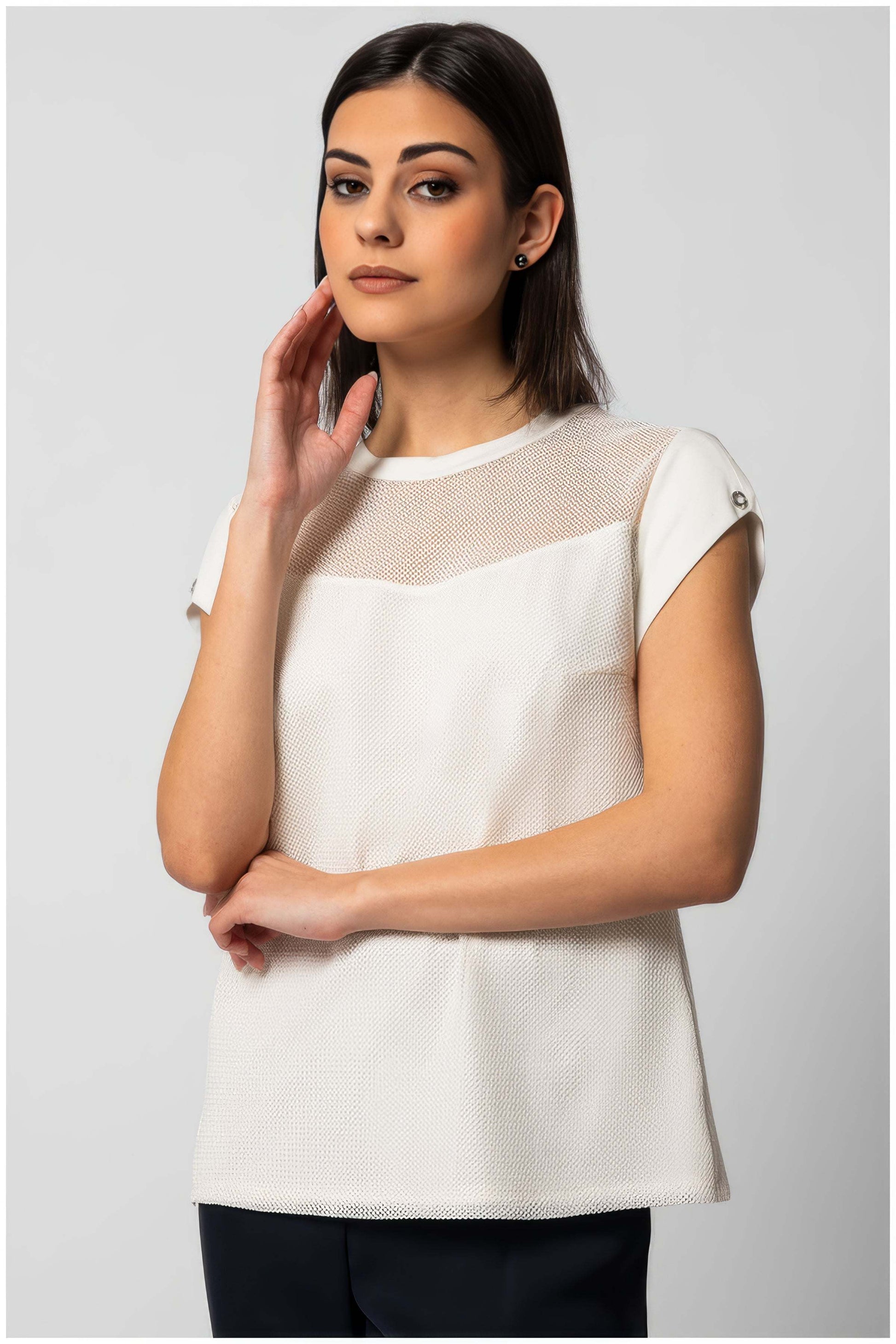 Woman wearing Aria Short-Sleeve Blouse in White with mesh detail and button accents on sleeves against gray background