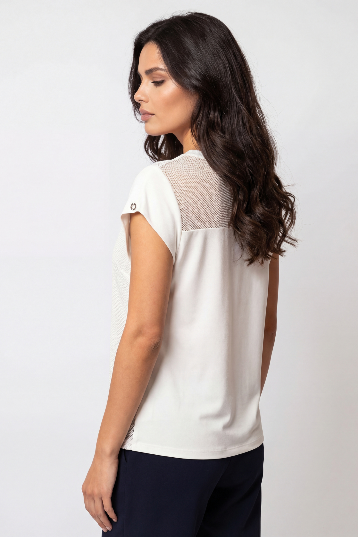 Woman wearing a white blouse with a subtle pattern on a plain background