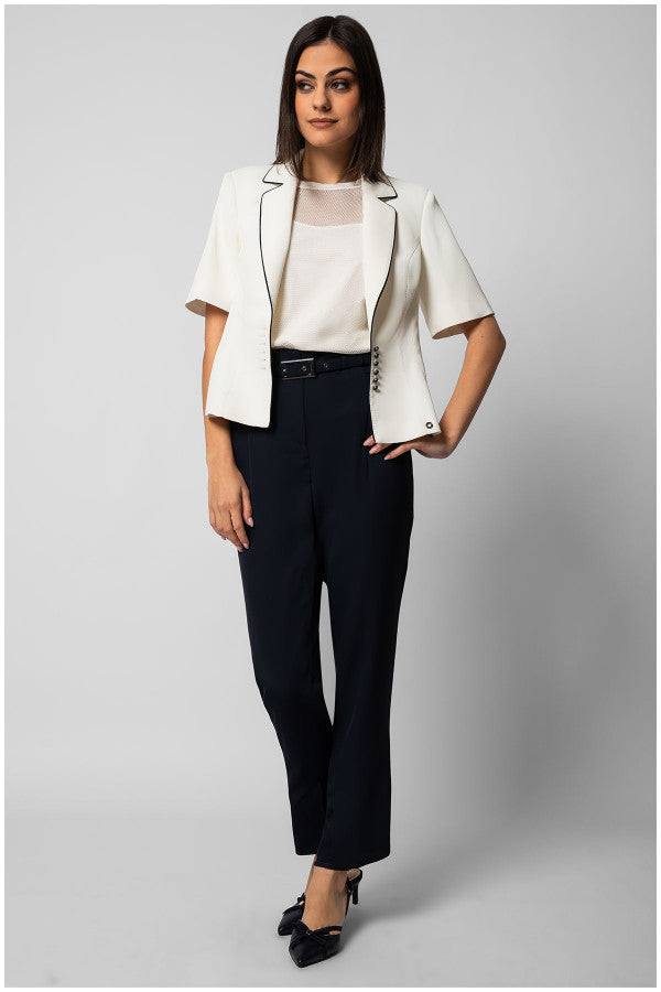 woman wearing white short-sleeve Aria top with sheer neckline and white blazer paired with black trousers and black heels