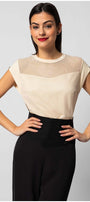 Woman wearing a cream womens short sleeve blouse with sheer paneling at the neckline paired with black pants