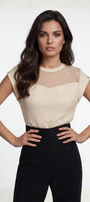 Woman wearing a beige top with mesh detail and black pants on a white background