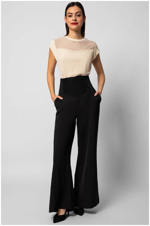 Womens short sleeve blouse with sheer neckline panel paired with black wide-leg trousers.