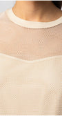 close-up of womens short sleeve blouse with textured fabric and sheer panel at neckline in beige color