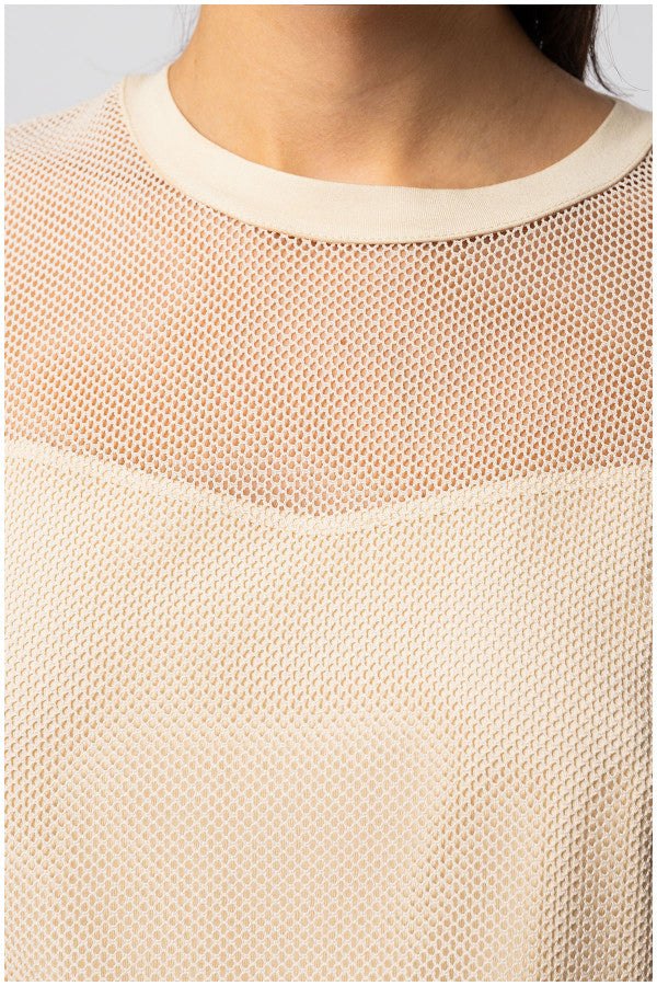 close-up of womens short sleeve blouse with textured fabric and sheer panel at neckline in beige color