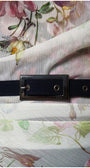 Close-up of floral sheer fabric layered over navy fabric with decorative black belt buckle on floral overall Tina