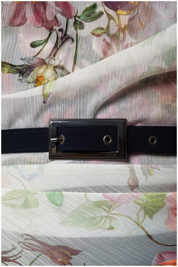 Close-up of floral sheer fabric layered over navy fabric with decorative black belt buckle on floral overall Tina