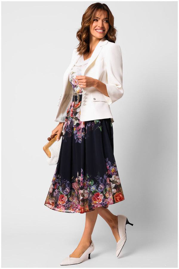 Woman wearing a flowing elegant midi dress Julia Dress with a statement belt and white tailored jacket, carrying a handbag