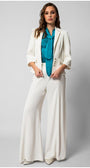 Woman wearing a white tailored blazer with wide-leg trousers and teal blouse featuring a bow tie neck detail.