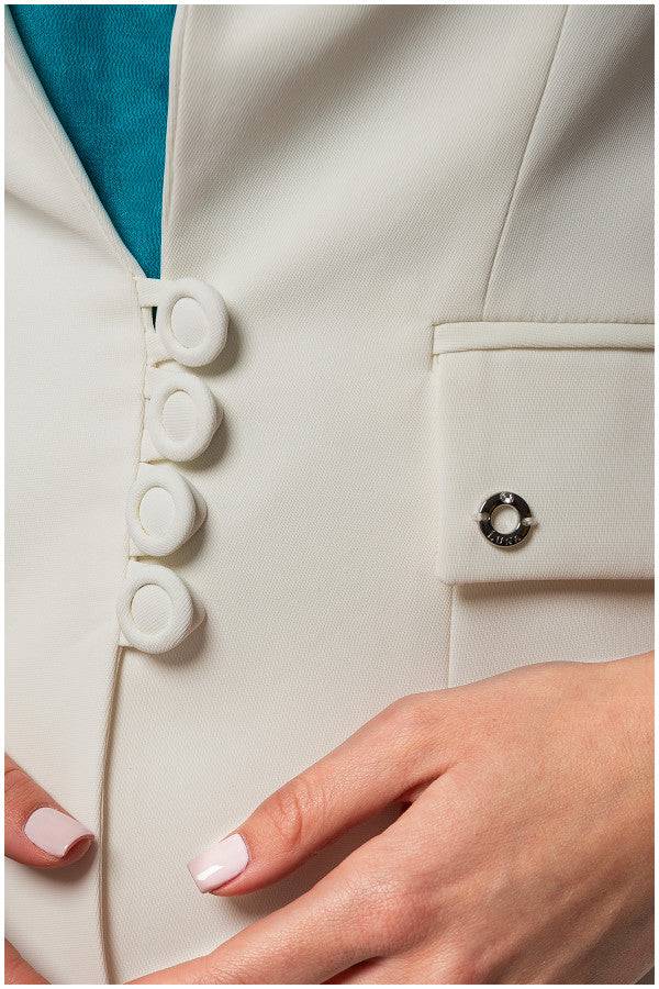 Close-up of white fitted blazer with covered buttons and tailored pocket detail on sleeve cuff.