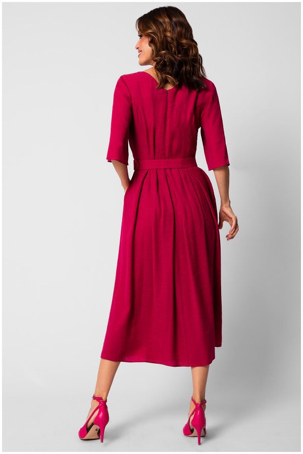 Woman wearing a fitted elegant midi dress in vibrant pink with half sleeves, pleated skirt, and matching high heels viewed from the back.