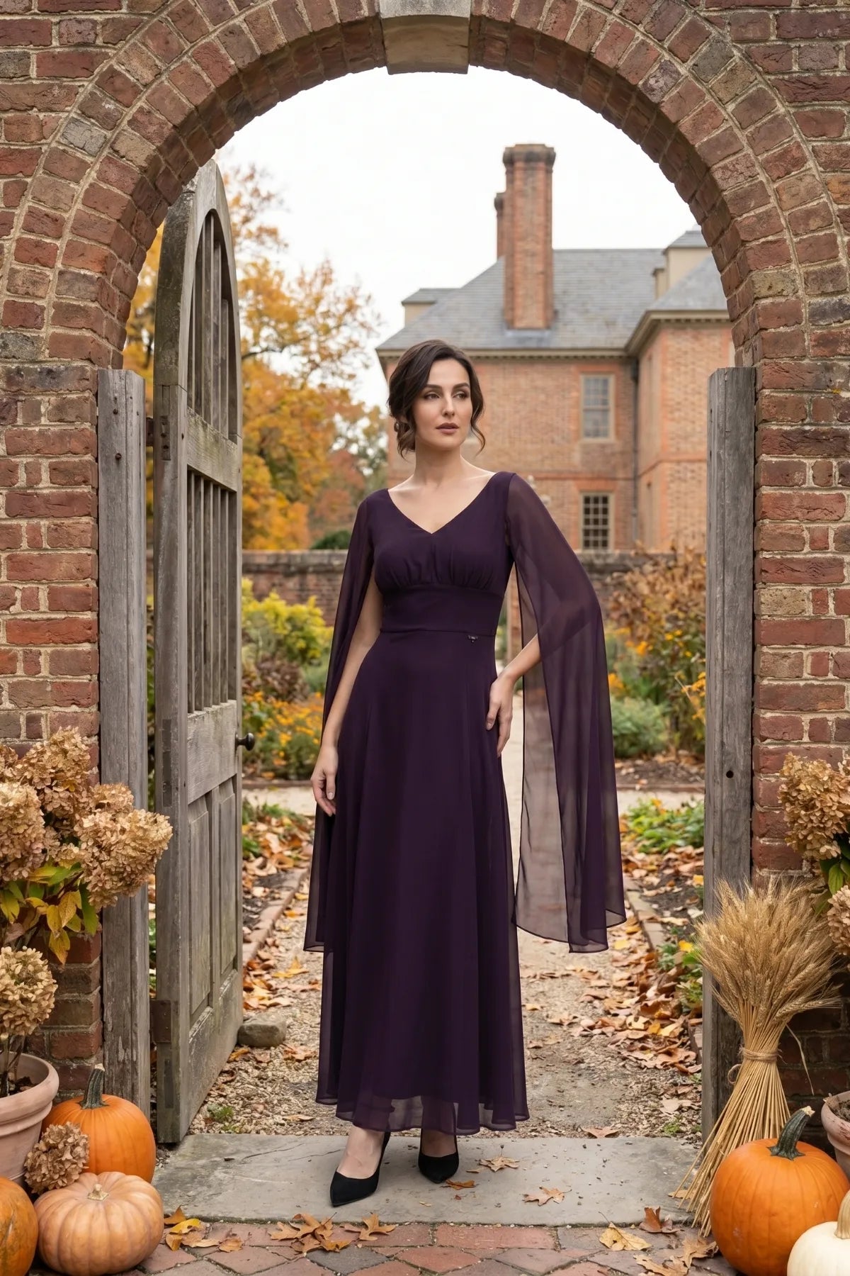 Rebeka plum drape-sleeve gown worn against an autumn stone setting with falling leaves
