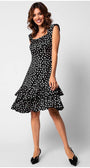 Woman wearing a fitted ruffle satin dress with white polka dots and tiered ruffle hem, smiling and posing standing.