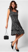 Woman wearing a black and white polka-dot ruffle satin dress hem holding matching purse and black heels