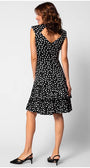 Woman wearing a black and white polka-dot fitted satin dress with tiered ruffle hem and V-back detail