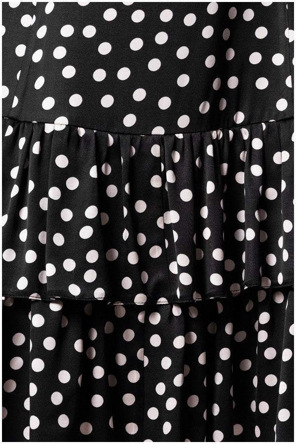Close-up of black satin fabric with white polka dots and tiered ruffle detailing on a dress hem