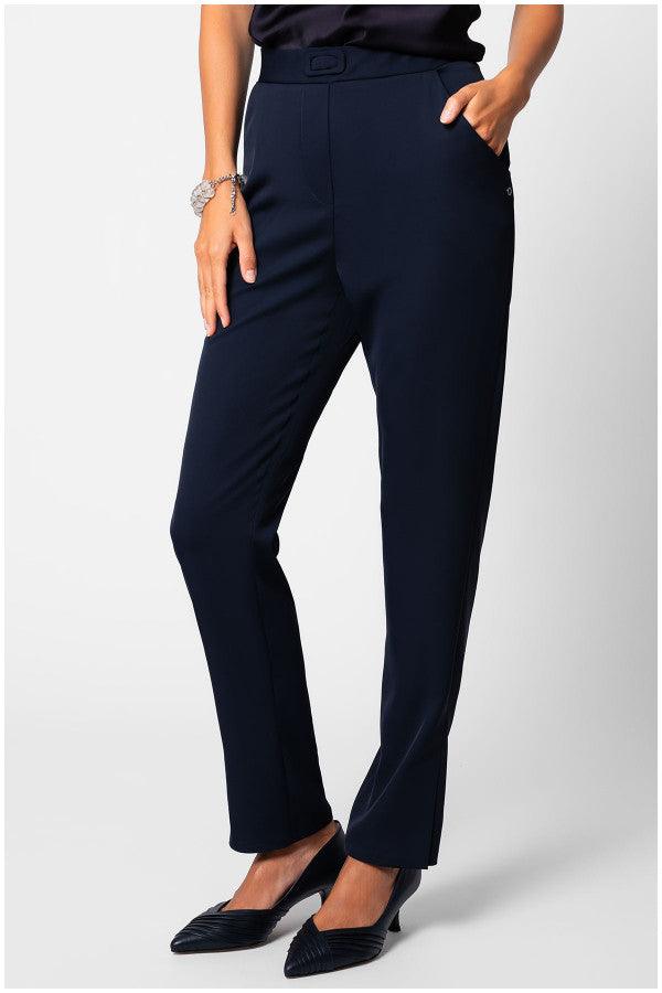 Woman wearing navy women travel pants Teodora stretch fabric straight-leg trousers paired with black heels and black top, hand in pocket