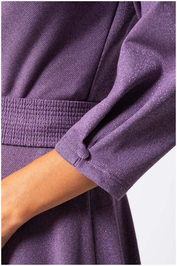 Close-up of a person wearing a purple garment with a white background