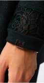 Close-up of a black textured sleeve with a floral pattern and a brand logo on a neutral background. Luna Fashion House