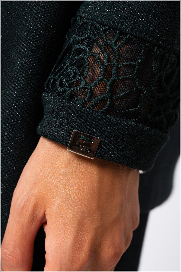Close-up of a black textured sleeve with a floral pattern and a brand logo on a neutral background. Luna Fashion House