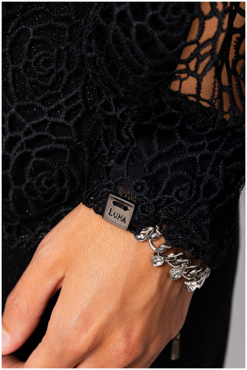 Close-up of a hand wearing a black lace sleeve with a Luma bracelet.