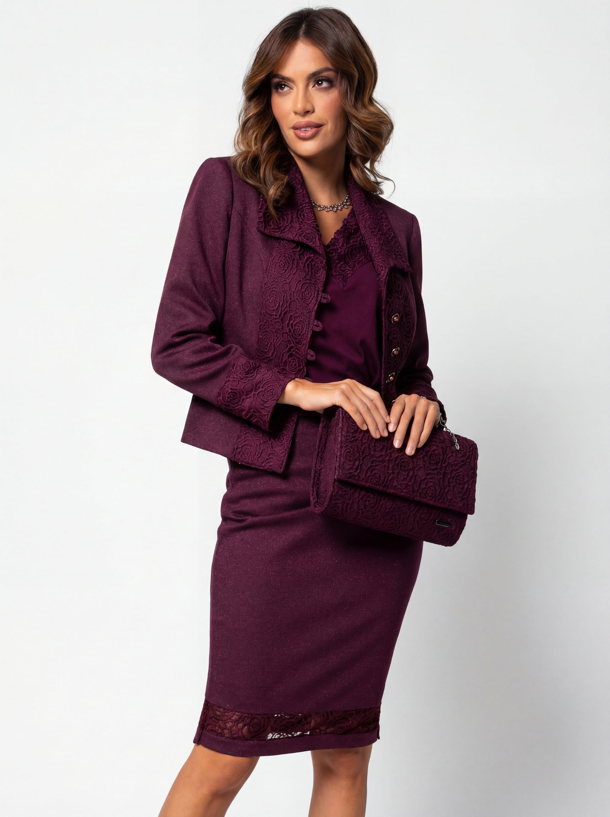 Woman wearing a purple outfit with a matching clutch against a white background