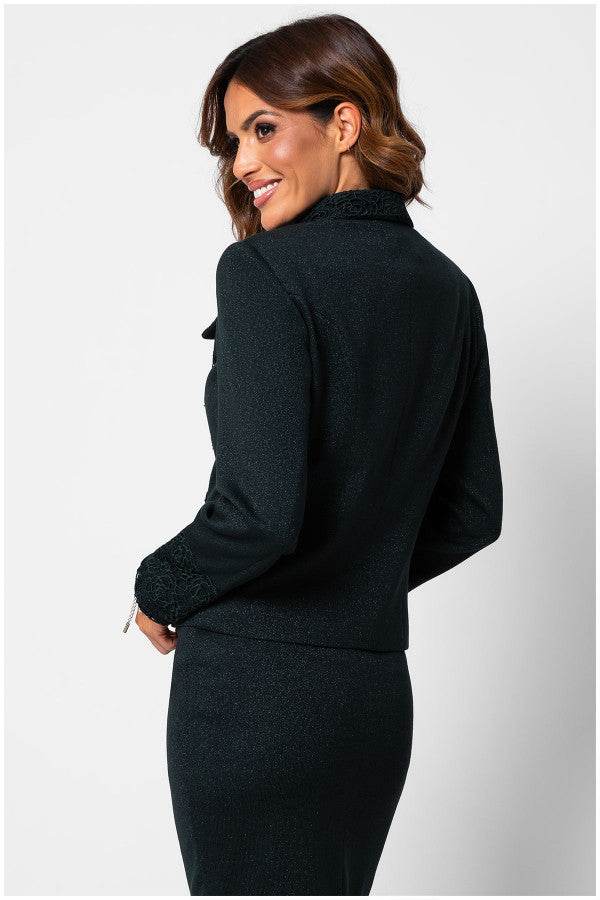 Woman wearing a fitted midnight green lace tailored blazer with detailed collar and cuffs, smiling and looking over her shoulder.
