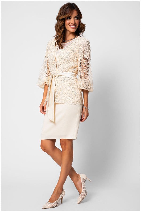 Woman wearing an elegant ivory fitted lace cocktail dress with soft draped waist and short lace sleeves, styled with matching heels.