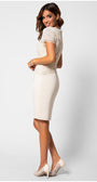 Woman wearing an ivory fitted lace cocktail dress with short sleeves and elegant tailored silhouette, posing sideways and smiling.