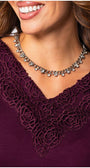Close-up of a woman wearing the bordeaux lace elegant blouse  Top Jody with intricate lace neckline detail and a silver charm necklace.