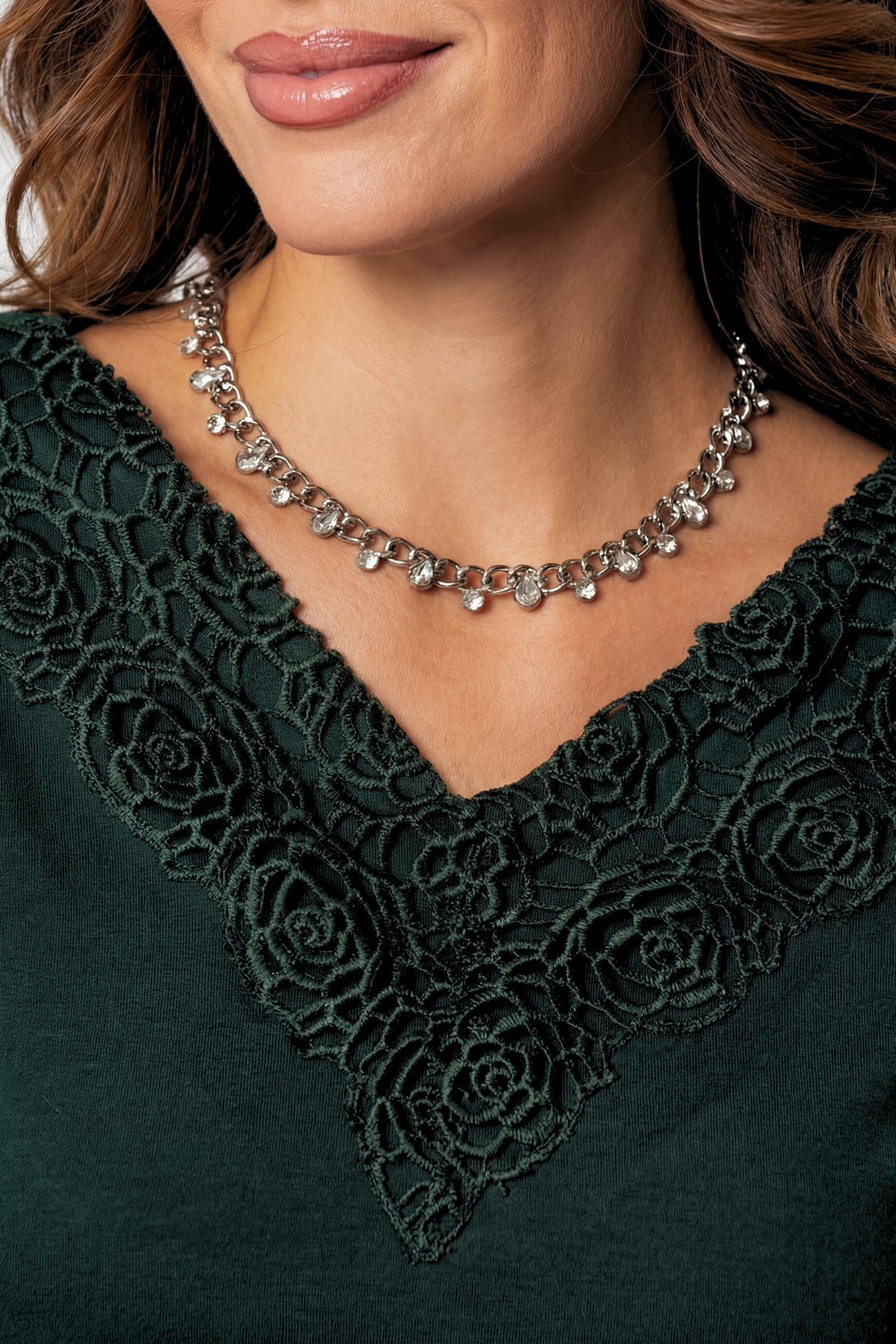 Close-up of a woman wearing a green lace-trimmed top and silver necklace.
