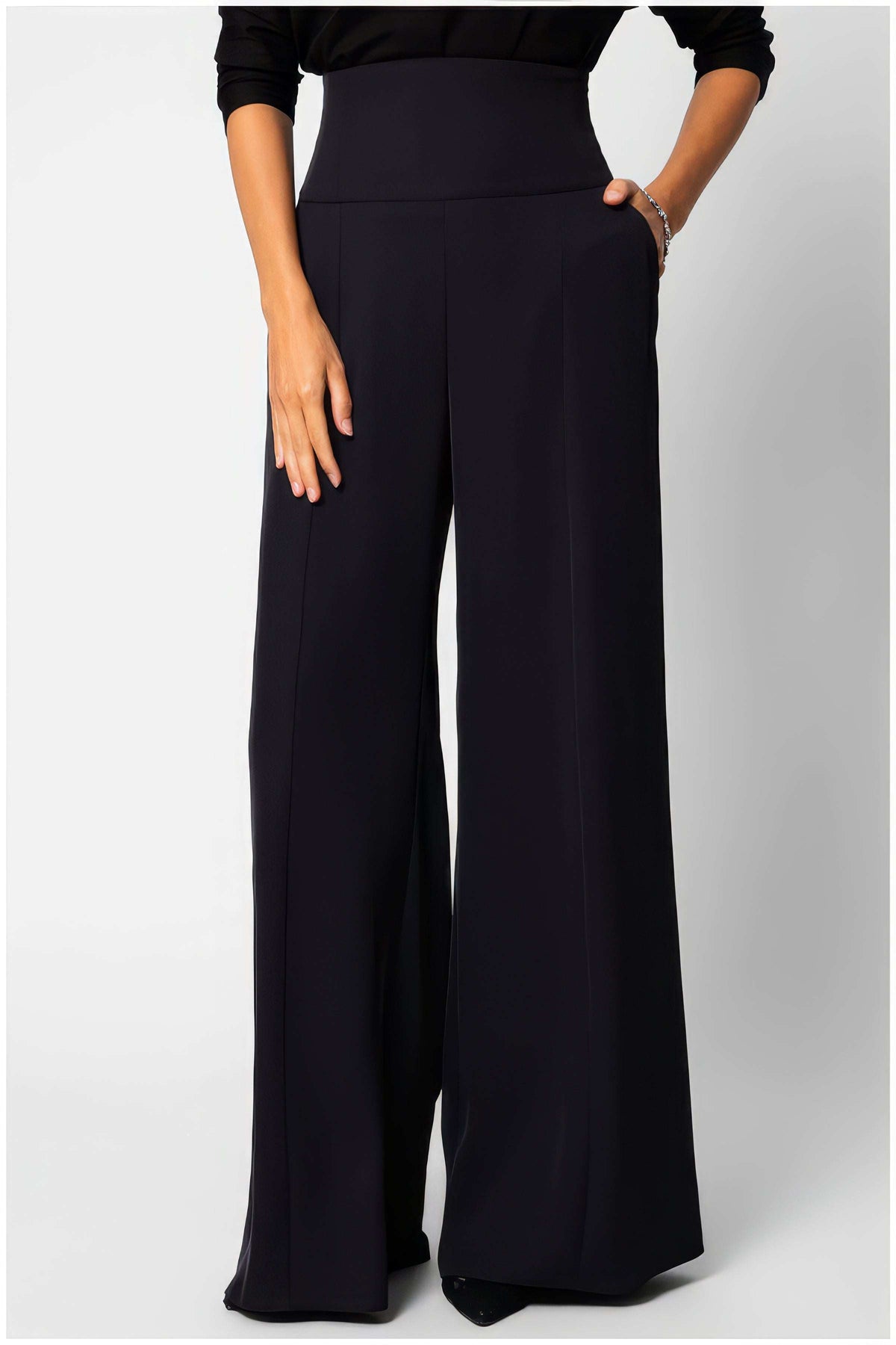 Black High Waisted Wide Leg Pants, Agatha. Wide-leg trousers. High waistband, pressed front crease, side pockets, worn with a black top.