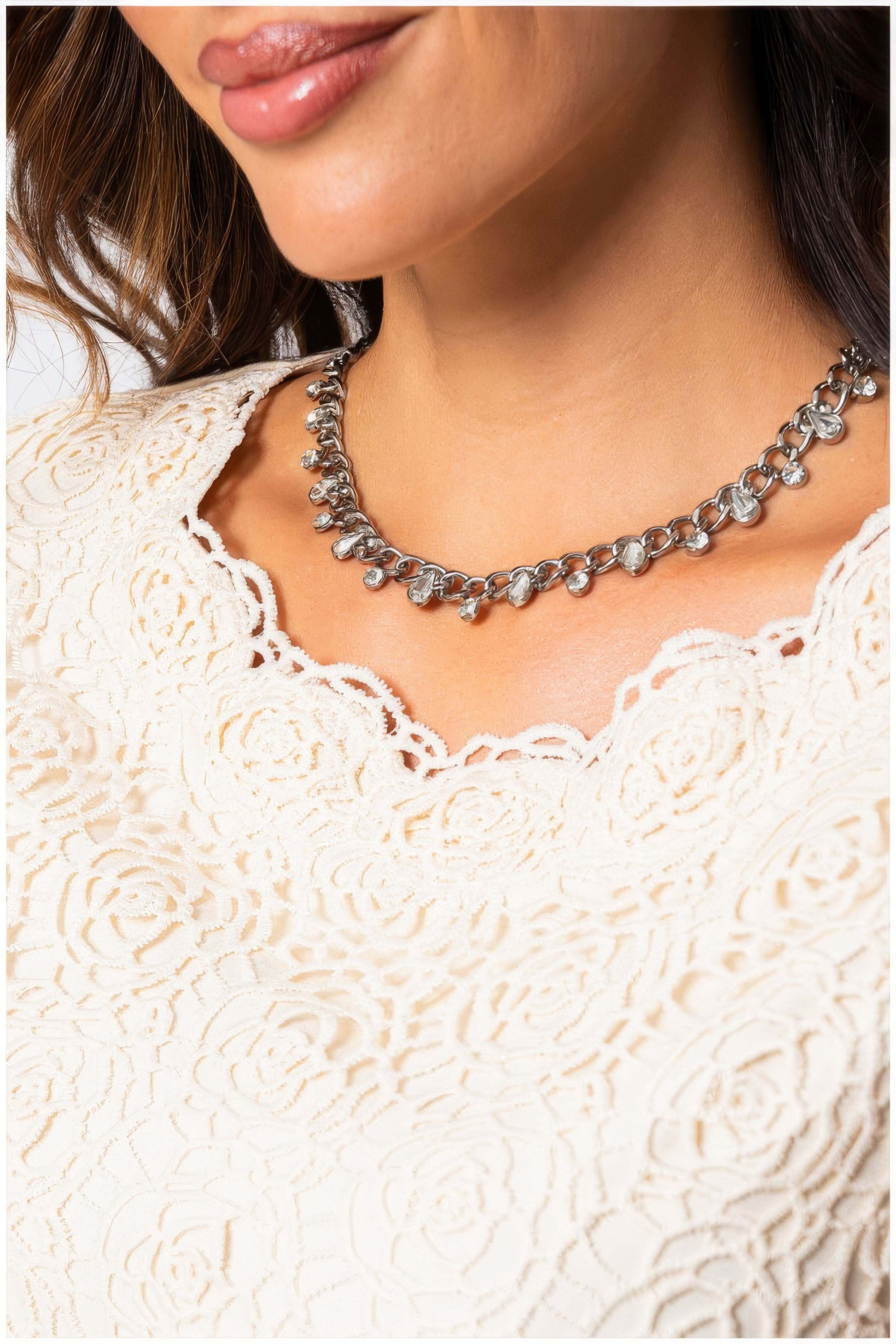 Close-up of a woman wearing the Jody Elegant Lace Blouse in Ivory with delicate lace detailing and a silver necklace