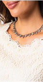 Close-up of ivory lace elegant blouse Jody neckline featuring delicate floral pattern and silver chain necklace detail.