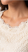 Close-up of a person wearing a white lace garment with floral patterns.