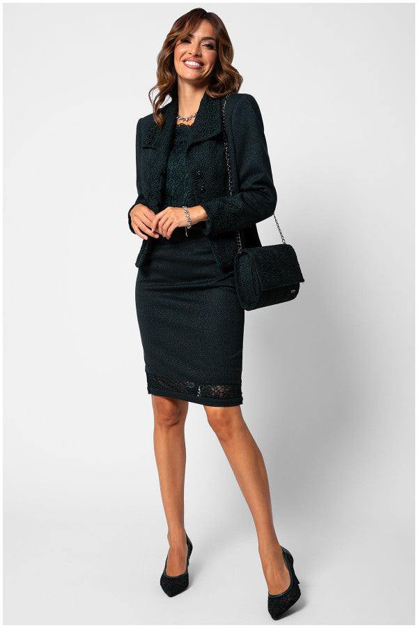Woman wearing elegant blouse Midnight Green Blouse Jody with lace overlay paired with matching skirt and jacket, holding a handbag