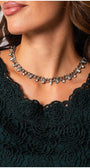 Close-up of a woman wearing the elegant blouse Midnight Green Jody Blouse with floral lace overlay and a silver charm necklace