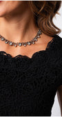 Close-up of black lace elegant blouse with floral details worn with silver chain necklace on woman