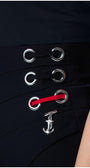 Close-up of black Tailored Wide Leg Pants Greta pants waistband with silver eyelets, red lace detail, and an anchor charm accessory.