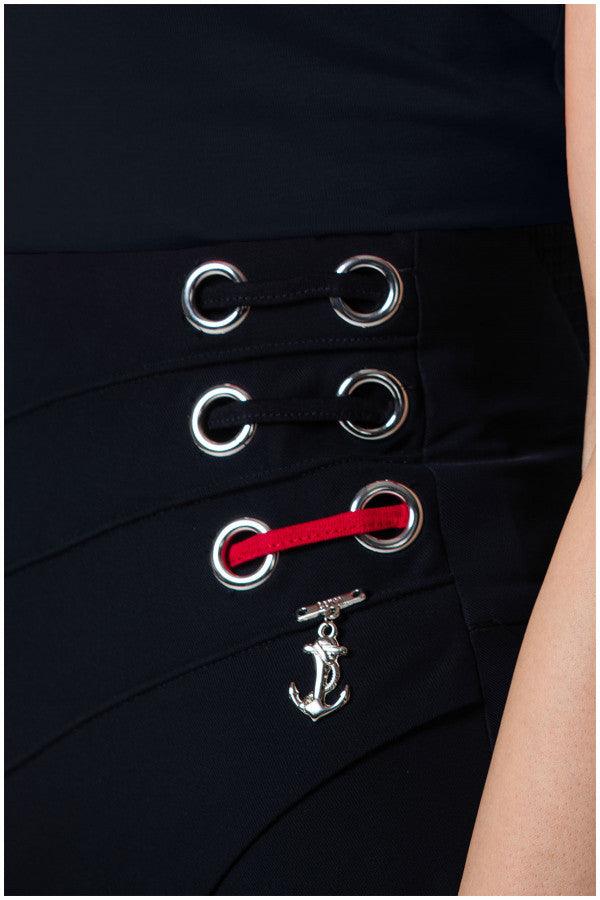Close-up of black Tailored Wide Leg Pants Greta pants waistband with silver eyelets, red lace detail, and an anchor charm accessory.