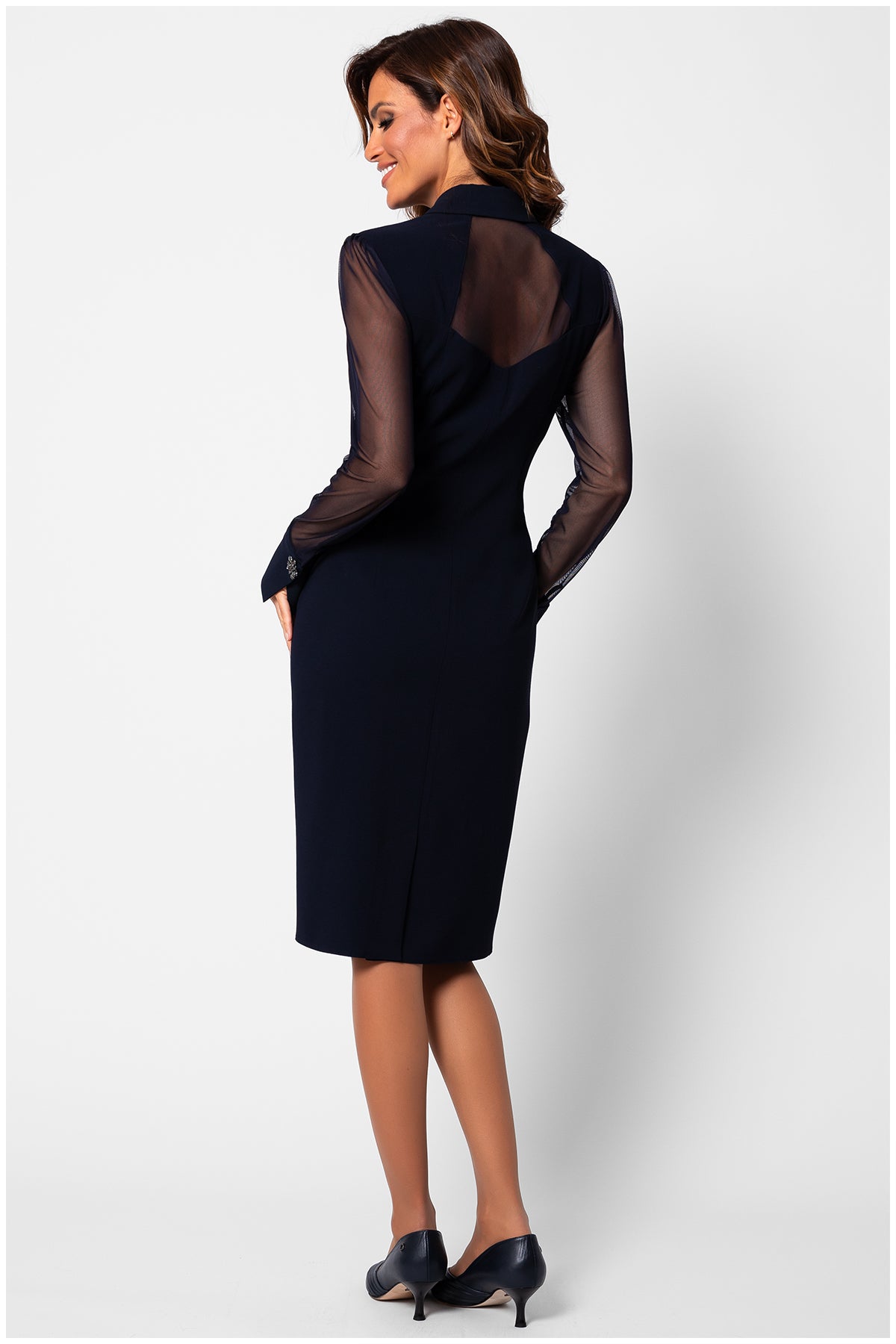 Woman wearing a black dress with sheer sleeves on a white background