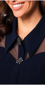 Close-up of a person wearing a navy blue outfit with a decorative brooch.
