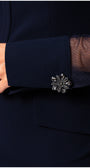 Navy blue cuff with a decorative silver brooch on a dark background