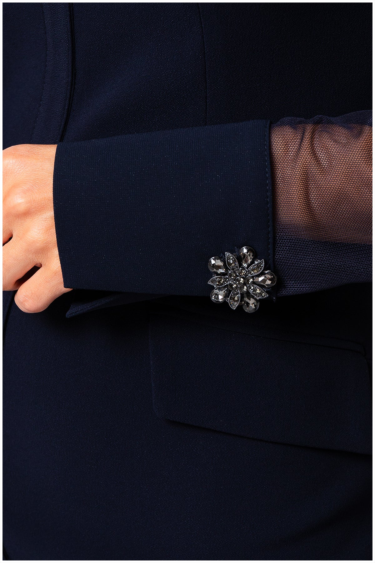 Navy blue cuff with a decorative silver brooch on a dark background