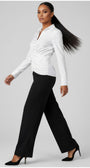 Woman wearing a white blouse and black pants on a gray background