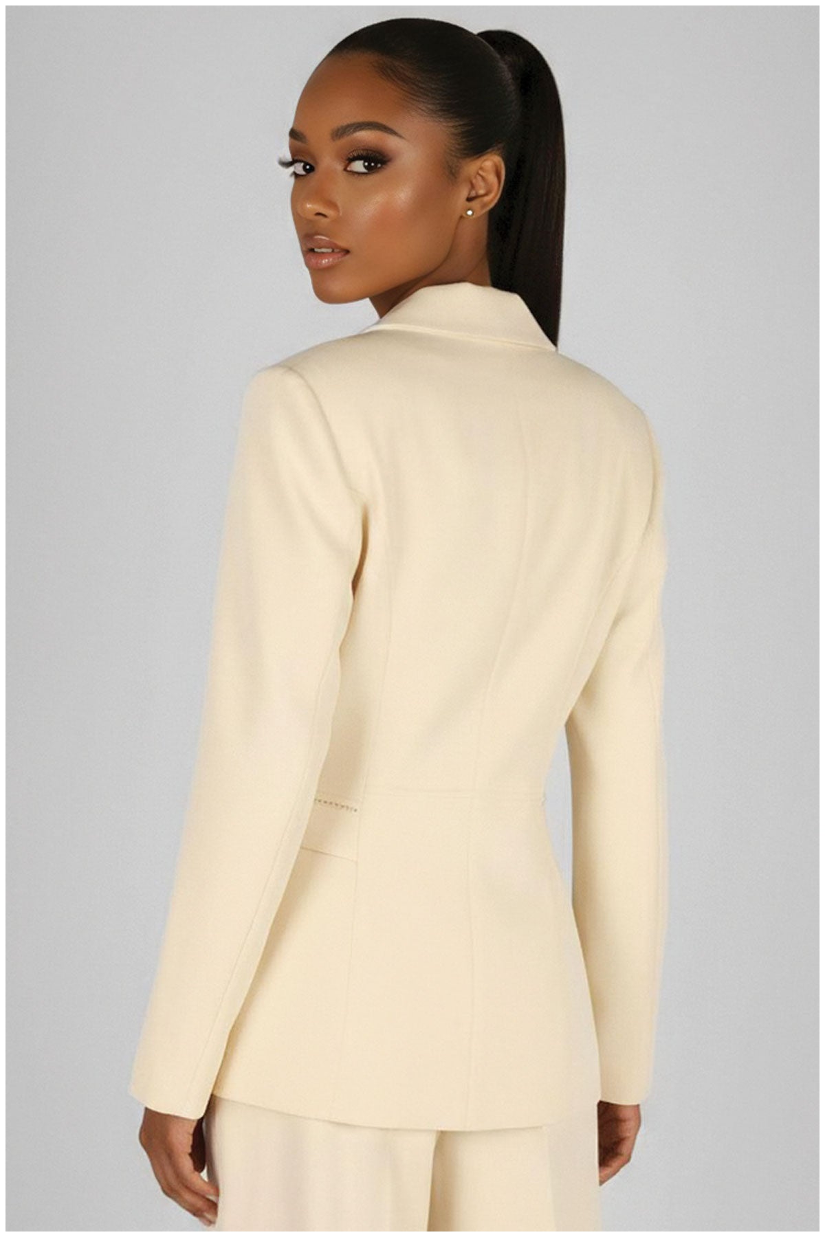 Woman wearing a light-colored suit against a plain background