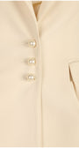 Close-up of a beige coat with pearl buttons on a beige background